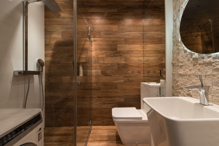 A bathroom with wooden tiles on the floor and walls in a neutral color scheme.